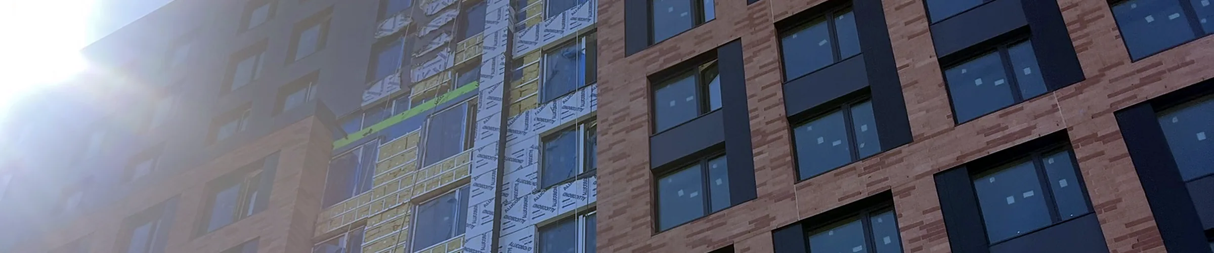 A multifamily building mid-construction, with its facade half clad