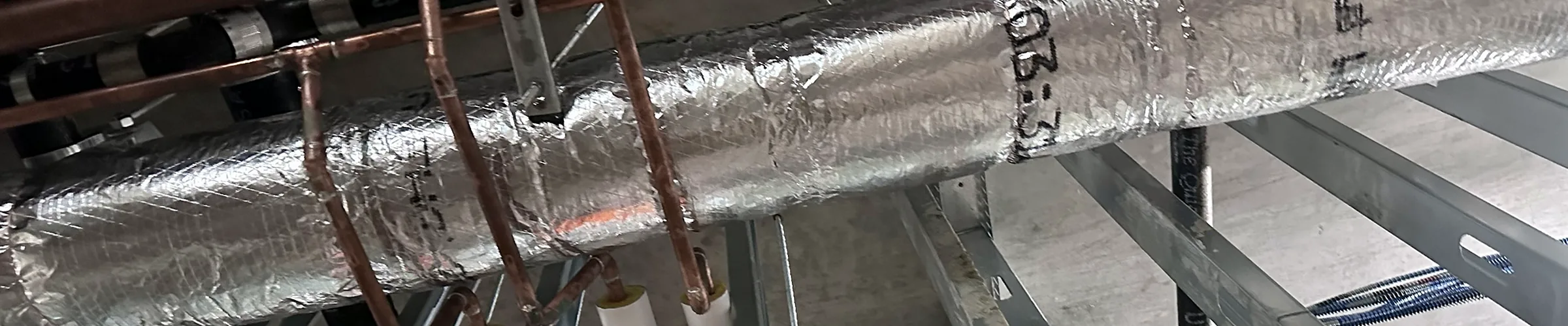 Insulated piping and copper lines running through light-gauge steel framing