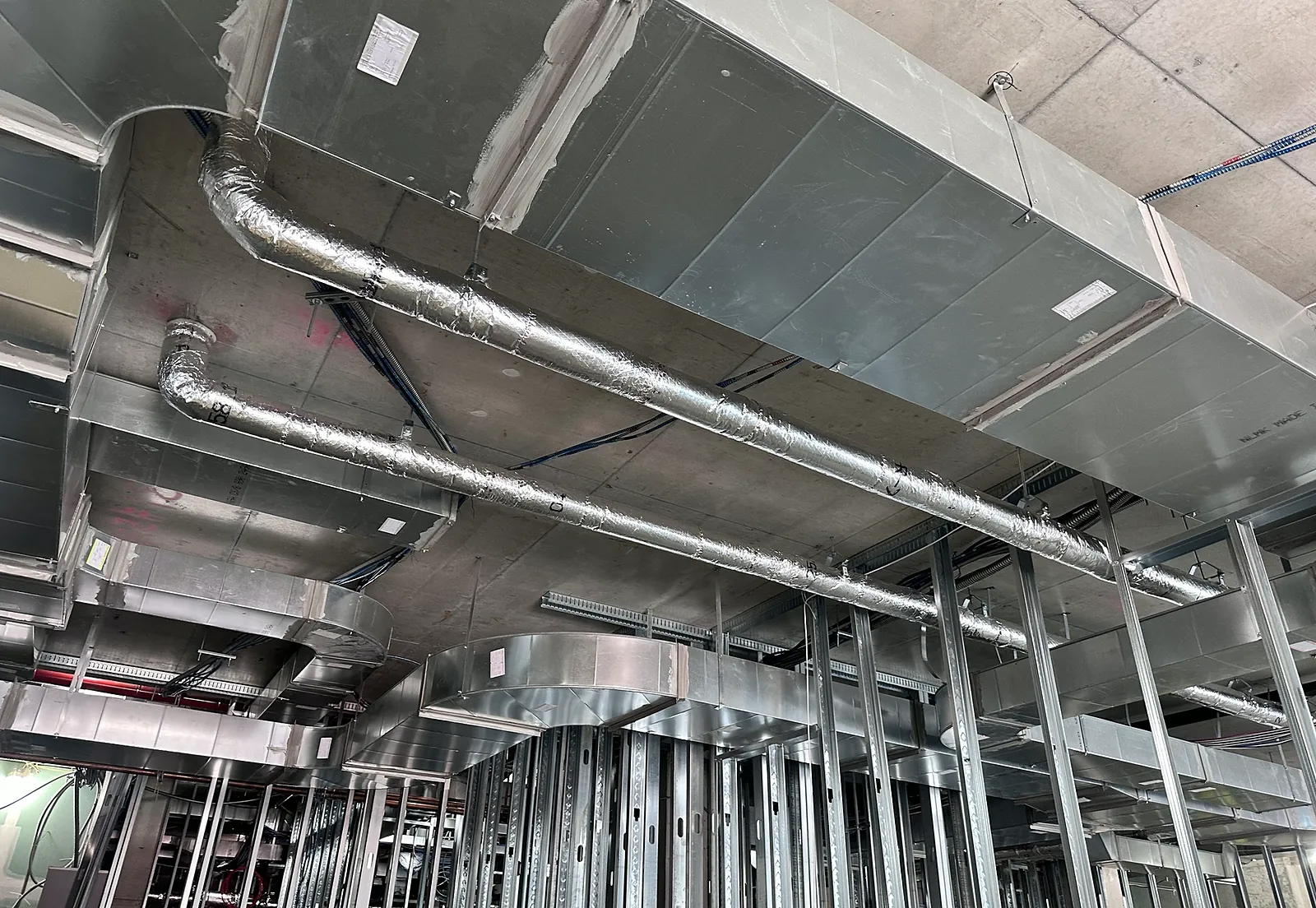 Exposed supply ductwork and insulated piping at ceiling level